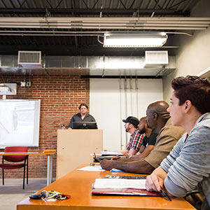 Male students focusing on teacher at front of room