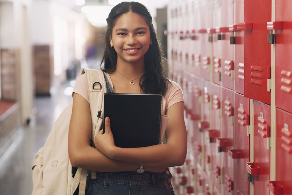 Student standing in high school hallway near lockers