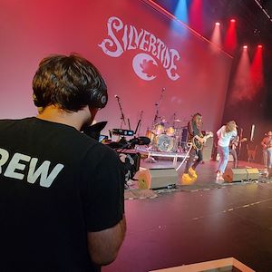 Student operating a camera during a band performance