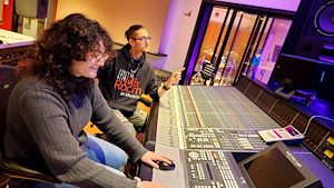 Student sitting at Atmos mixing table with insturctor