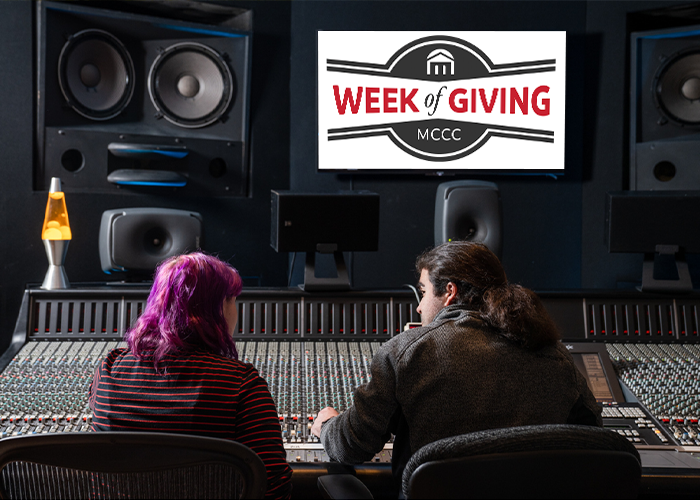 Two students sitting in front of a sound mixing board