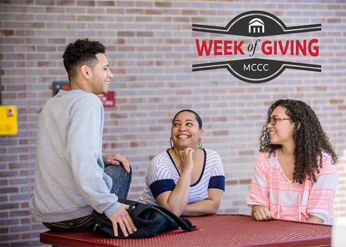 Three students sitting in front of brick wall chatting