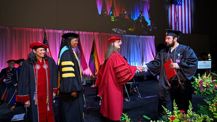 MCCC President shakes graduate's hand on stage at commencement 2024