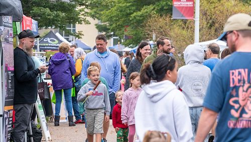 A crowd fills the walkway on the Blue Bell Campus during the Whitpain Festival. Vendors line the edges.