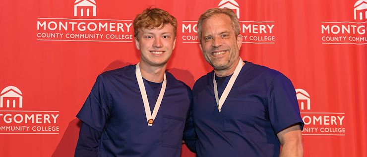 David and Aiden Gawel Father and son David and Aiden Gawel stand together wearing nursing scrubs in front of a red Montgomery County Community College backdrop