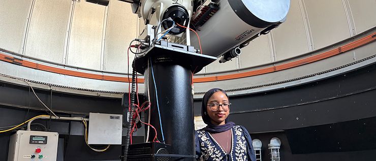 Loujain Ahmed next to a telescope in the observatory on the Blue Bell Campus