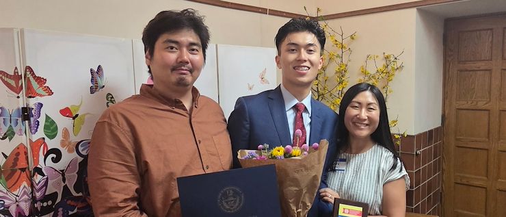 Vincent Nguyen Vincent Nguyen, ’26 stands in between Jay Lee on the left and Kate Firestone on the left. Vincent is holding a bouquet of flowers. Jay Lee is holding a certificate and Kate Firestone is holding a small plaque.